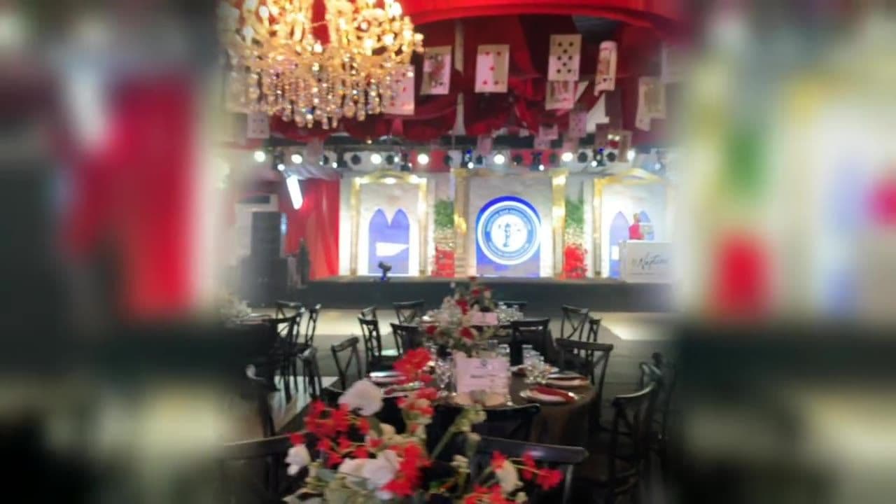 Draped event hall with chandeliers, stage backdrop and dressed banquet tables